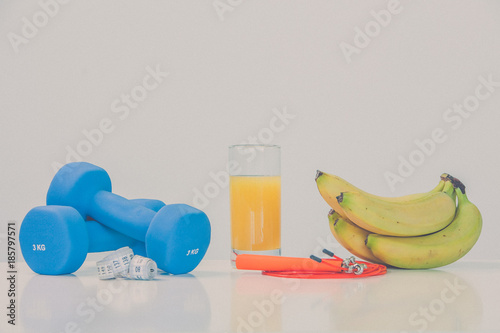 The concept of a healthy diet. Small dumbbells. Orange juice. Bananas. The skipping rope. Measuring tape waist. on a white background. healthy lifestyle. sport. Fitness food.