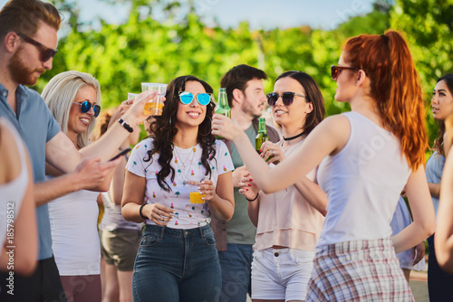 Group of people standing, drinking an having a good time at outdoor party