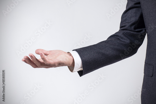 Man in suit shows outstretched hand with open palm. photo