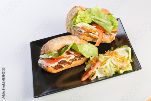 close up of BLT sandwich with salad on a black plate