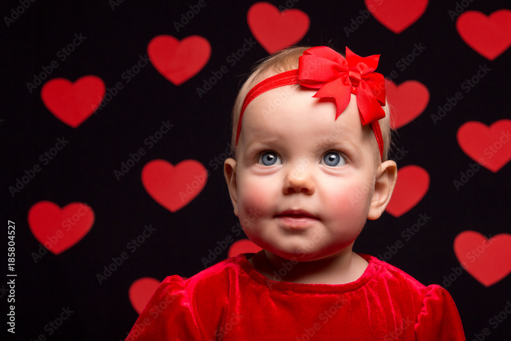 little baby girl in a red dress on a dark background with red hearts little baby girl in a red dress on a dark background with red hearts
