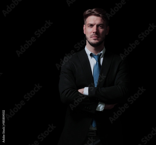 Handsome business man isolated on black with arms crossed