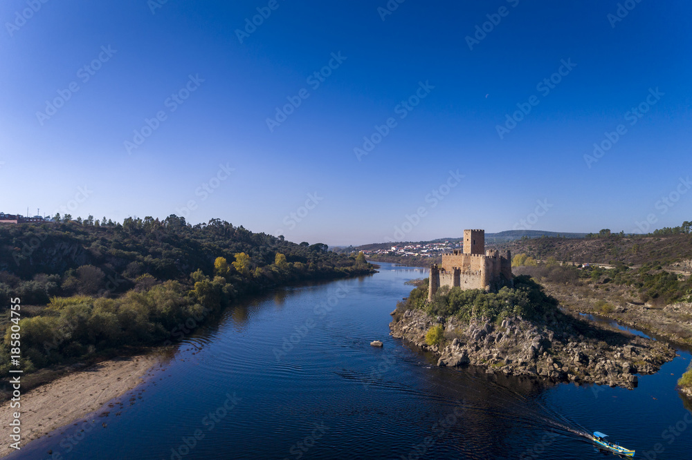 Aerial view of the Armourol Castle with a boat passing in the Tagus River in Portugal; Concept for travel in Portugal