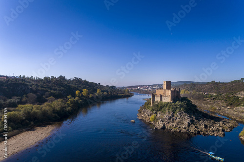 Aerial view of the Armourol Castle with a boat passing in the Tagus River in Portugal; Concept for travel in Portugal