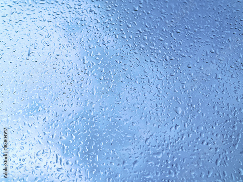 Raindrops on the windowpane on the background of a formidable blue sky. Natural background for sad mood and thoughts, demonstrations of weather