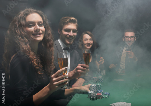 group of friends sitting at game table in casino