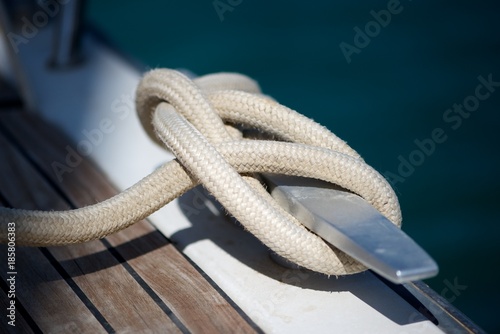 Closeup picture a rope tied to a metal cleat on a yacht deck. 