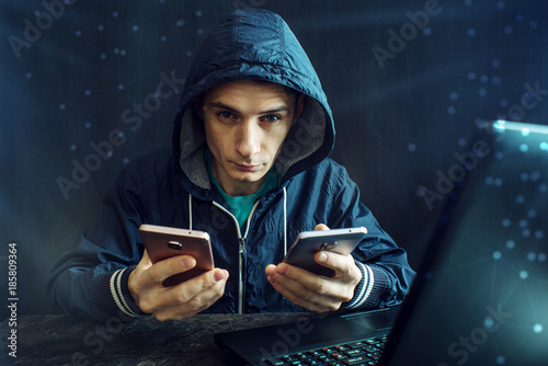 Male hacker uses the mobile phone to hack the system. Concept of cyber crime and hacking electronic devices