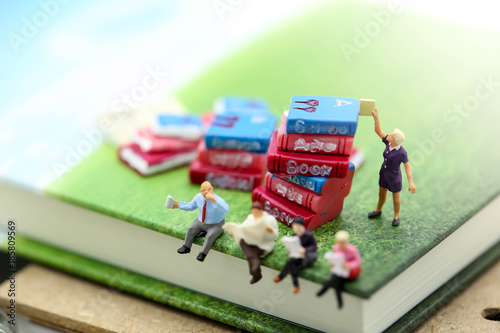 Miniature people : sitting on book using as background education or business concept.