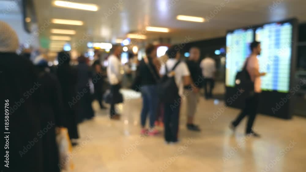 Blurred unrecognizable people walking in airport. Passengers going and watching at online scoreboard. Defocused background of big terminal with humans stepping for the flight. Slow motion Blurred unrecognizable people walking in airport. Passengers going and watching at online scoreboard. Defocused background of big terminal with humans stepping for the flight. Slow motion