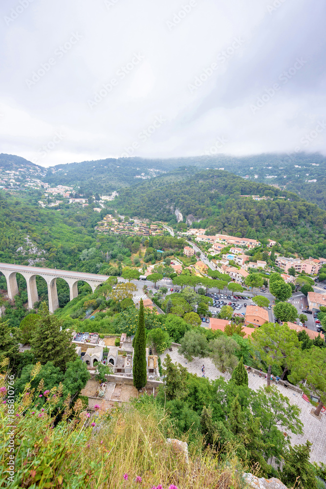 Daylight foggy view to Medieval stone arch bridge in the village of Eze