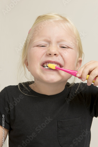 Portrait of Girl Brushing Her Front Teeth with Pink Toothbrush