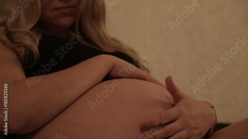 Pregnant girl sitting on the bed / Pregnant girl sitting on the bed stroking belly photo