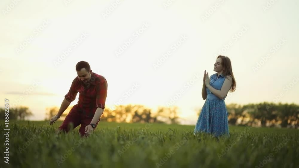 Beautiful young people in casual wear having fun in the green high grass, on the sunset, she smiles and claps to her dancing partner. Playful mood, true happiness, having a romantic date True emotions Beautiful young people in casual wear having fun in the green high grass, on the sunset, she smiles and claps to her dancing partner. Playful mood, true happiness, having a romantic date True emotions