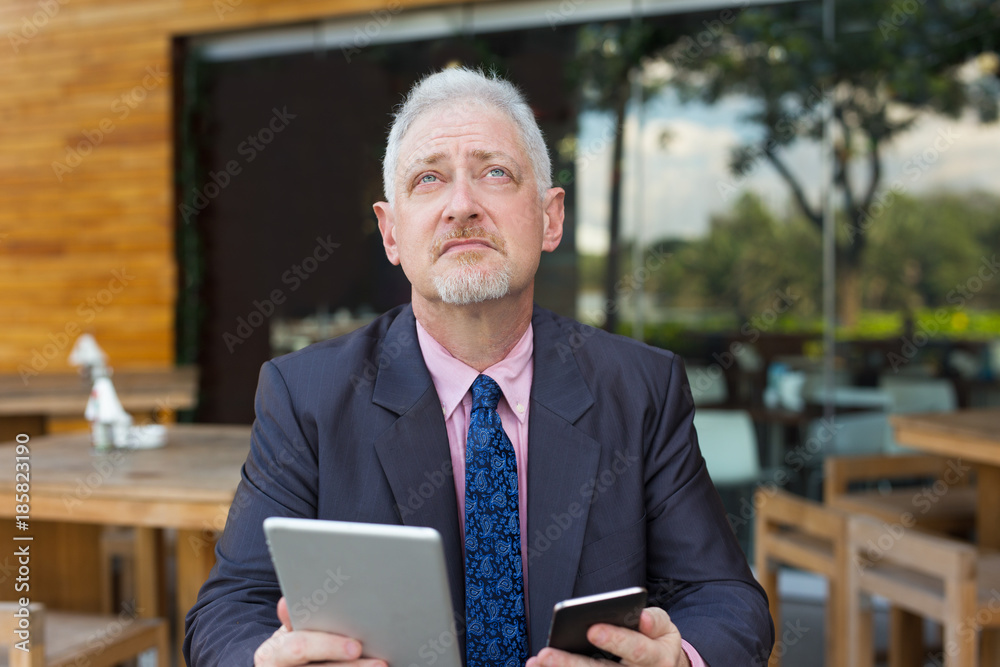 Pensive Boss Using Tablet and Smartphone Outdoors Pensive Boss Using Tablet and Smartphone Outdoors