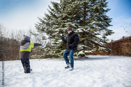 Father and Son having fun throwing snow outdoors during winter season.