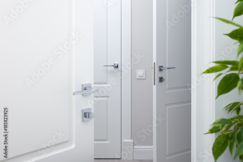 Open the white door into the corridor. Chrome modern door handles