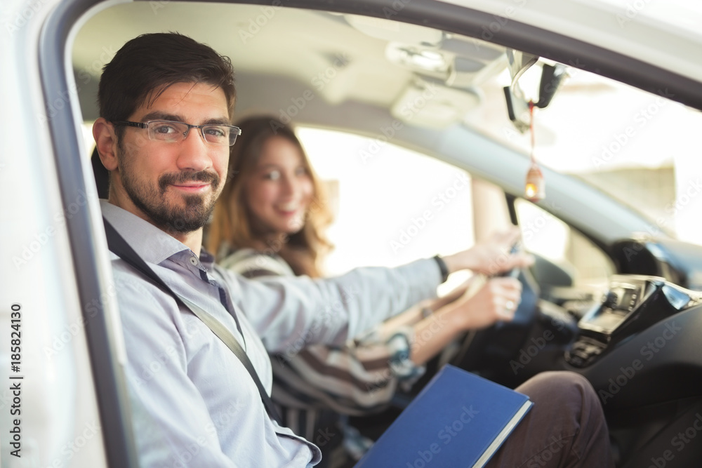 Driving instructor is teaching his student how to drive a car