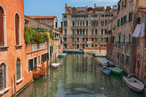 Traditional narrow canal street with gondolas and old houses in Venice, Italy. Architecture and landmarks of Venice. Beautiful Venice postcard.
