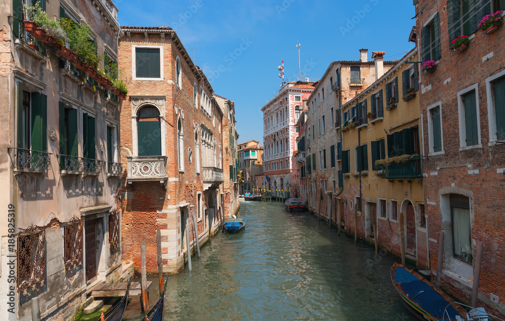 Traditional narrow canal street with gondolas and old houses in Venice, Italy. Architecture and landmarks of Venice. Beautiful Venice postcard.