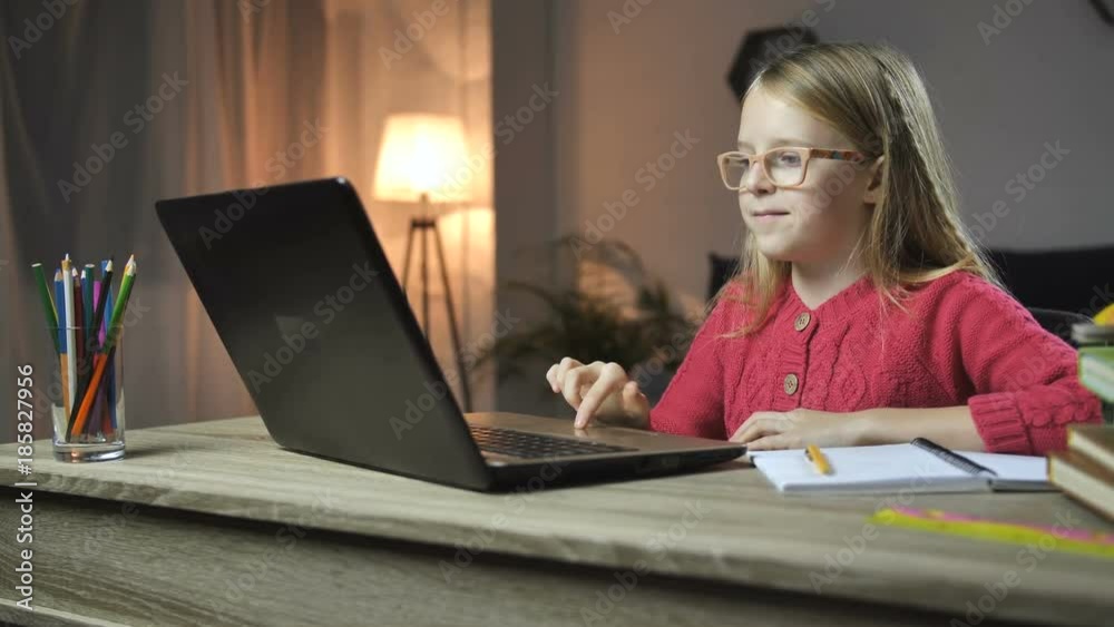 Cheerful child doing homework online with laptop Cheerful child doing homework online with laptop