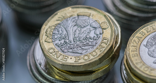 Close up focus photos of new United kingdom Pound coin, among other British coins photo