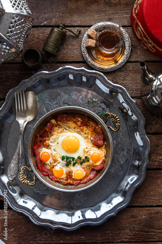 Turkish basturma with fried egg in a copper pan, rustic style