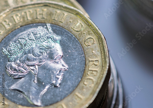 Close up focus photos of new United kingdom Pound coin, among other British coins photo