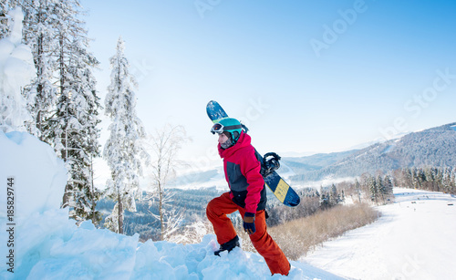 Shot of a male snowboarder carrying his board walking in the mountains on sunny winter day copyspace active sports lifestyle recreation seasonal people