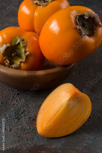 Fresh juicy persimmon on a dark background with copy space close-up