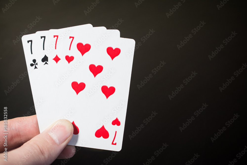 Abstract: man hand holding playing card four seven isolated on black background with copyspace Abstract: man hand holding playing card four seven isolated on black background with copyspace