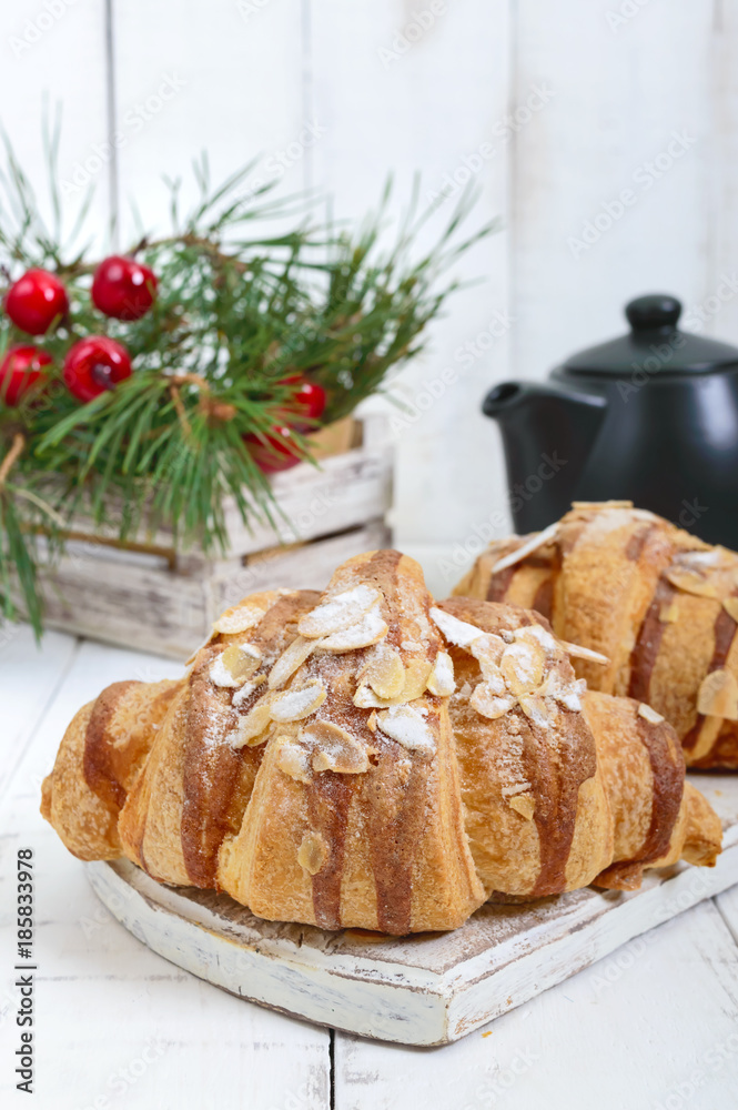 Large tasty croissants with almond flakes on a white wooden background. French pastries. Breakfast. Large tasty croissants with almond flakes on a white wooden background. French pastries. Breakfast.
