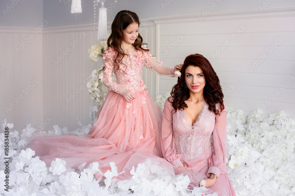 Mom and daughter in amazing dresses with flowers Mom and daughter in amazing dresses with flowers