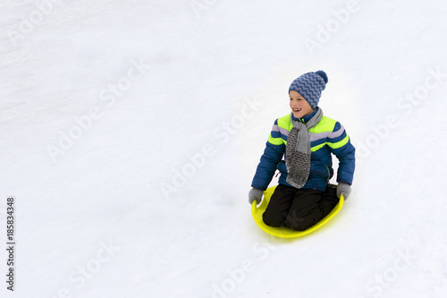 Kid slides down a hill on plate for driving on snow