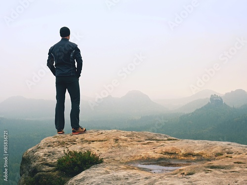 Hiker in sportswear stand on the peak of sandstone rock in rock empires park and watching over vallley