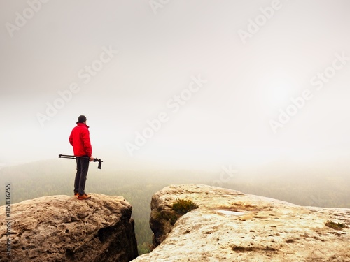 Nature photographer prepare camera to takes impressive photos of misty fall mountains. Tourist photographer