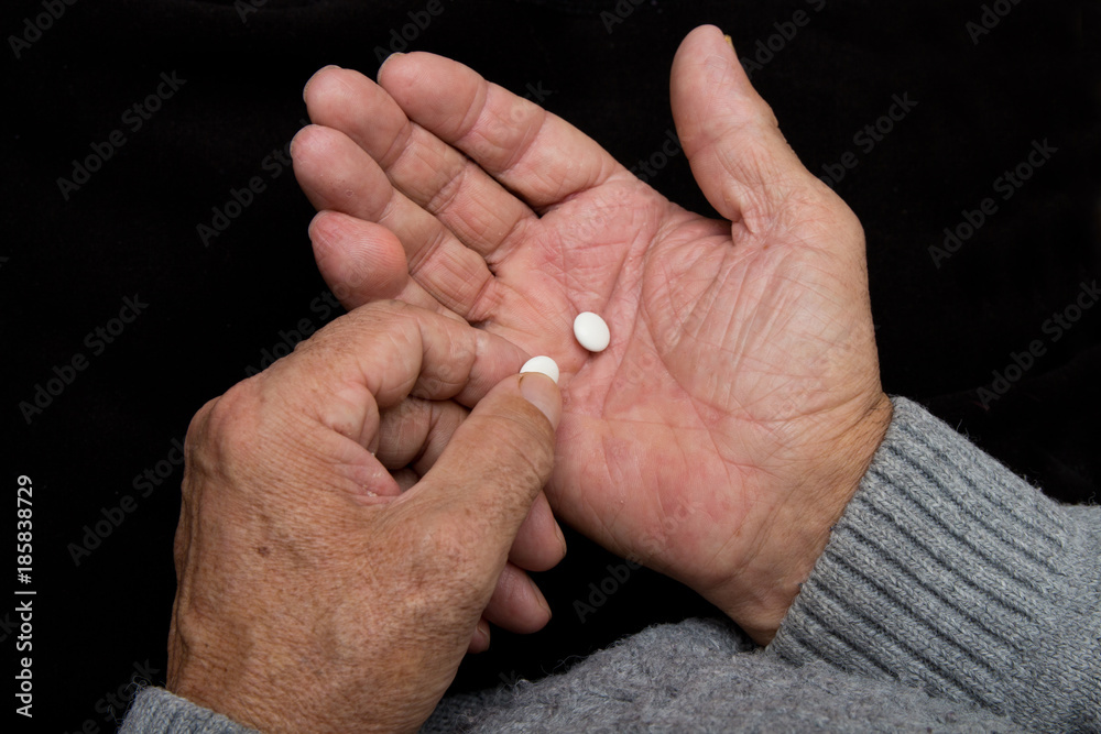 Fototapeta premium An elderly man holds a lot of pills in old hands. Painful old age. Health care of older people