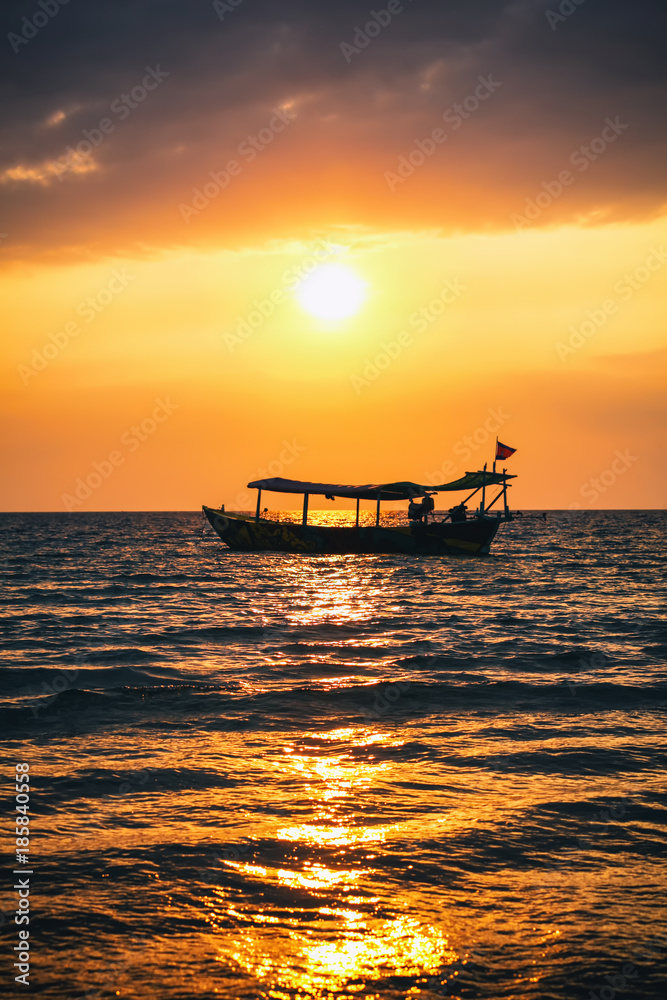 Fototapeta premium Bright red sunset on the beach with fishing boat in Cambodia, Sihanoukville.