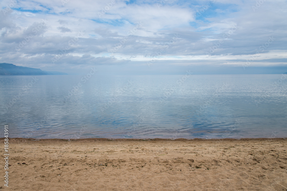 Clear crystal water of Lake Baikal in calm weather . Blue sky and clouds reflection. Clear crystal water of Lake Baikal in calm weather . Blue sky and clouds reflection.