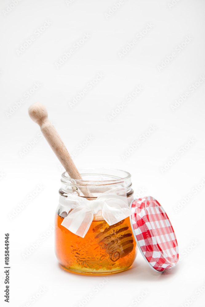 Close up of a decorative honey jar and honey spoon on a white background Close up of a decorative honey jar and honey spoon on a white background