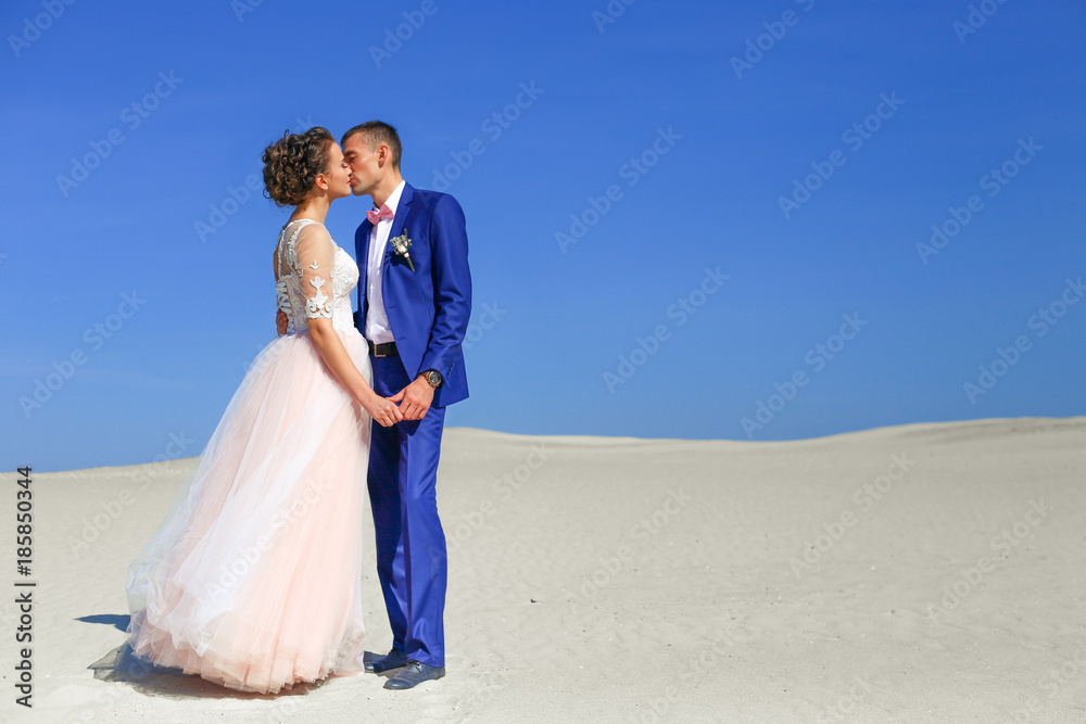 Young wedding couple on beautiful sand dune with wives on sea 