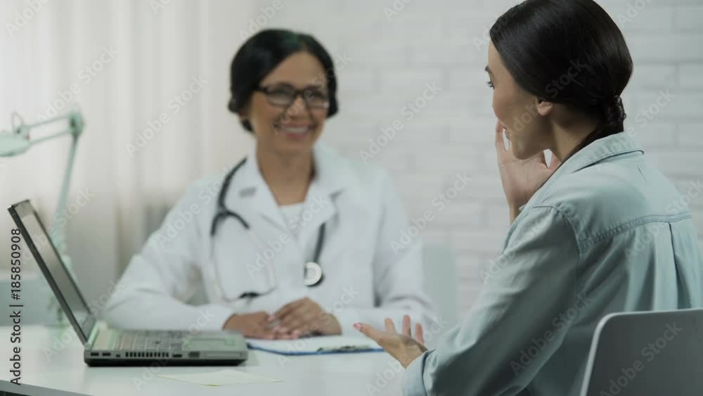 Physician informing patient about good news, showing test results on laptop Physician informing patient about good news, showing test results on laptop
