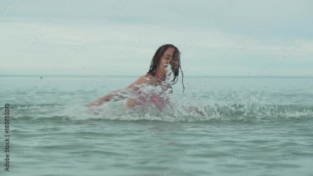 Joyful happy young girl playing with splashing water in sea slow motion stock footage video Joyful happy young girl playing with splashing water in sea slow motion stock footage video