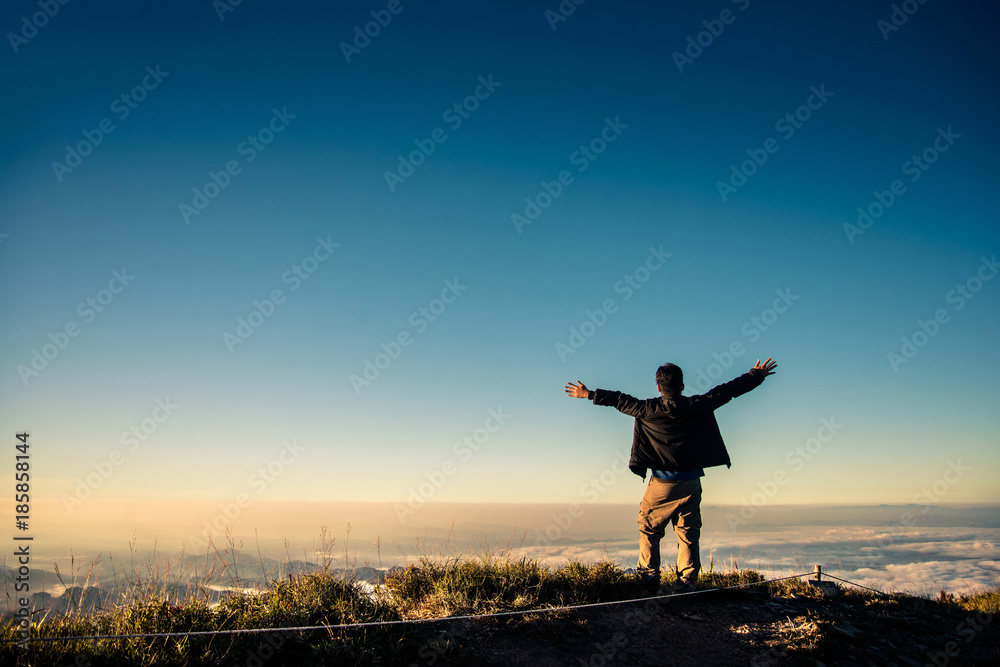Traveler hands raised standing on mountains cliff alone Traveler hands raised standing on mountains cliff alone