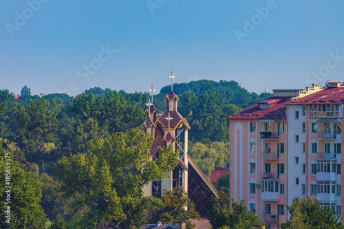 Modern buildings and church among the park trees, blue sky