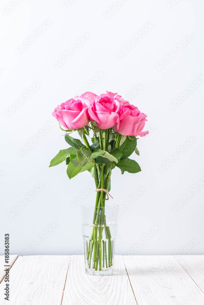 Naklejka premium pink rose in vase on wood background