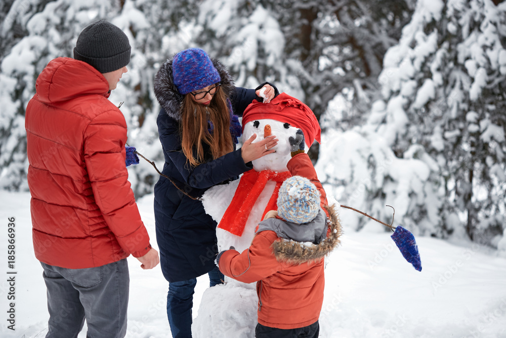 winter fun. a girl, a man and a boy making a snowman.