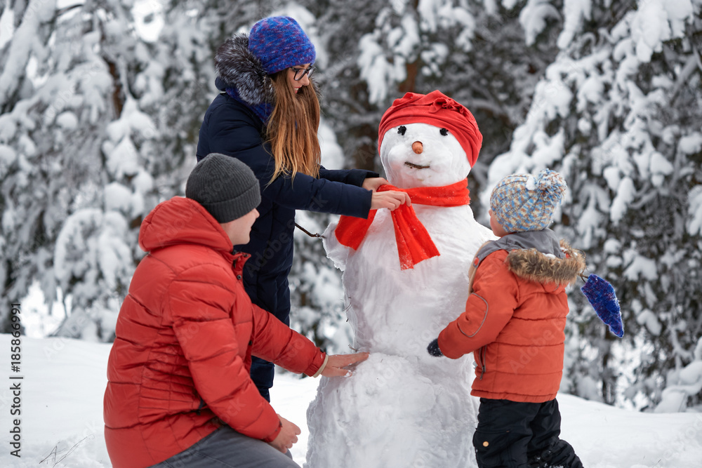 winter fun. a girl, a man and a boy making a snowman. winter fun. a girl, a man and a boy making a snowman.