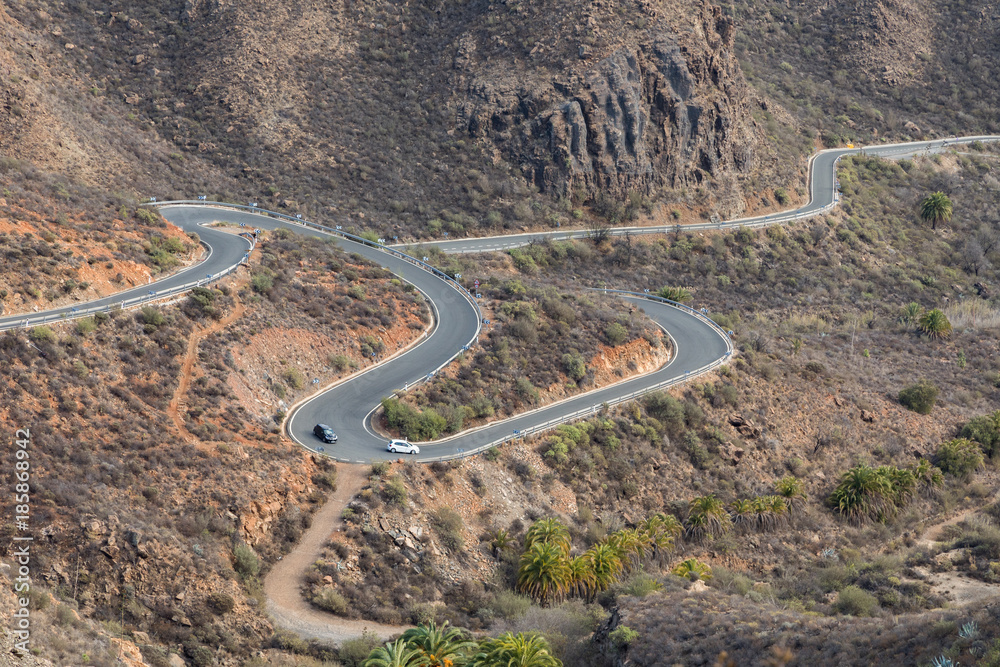 Curved winding road with two cars driving in the mountains in Gran Canaria