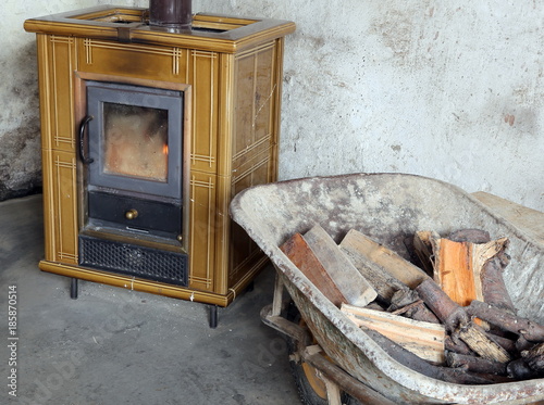 tiled stove and wheelbarrow full of firewood in the old mountain house photo